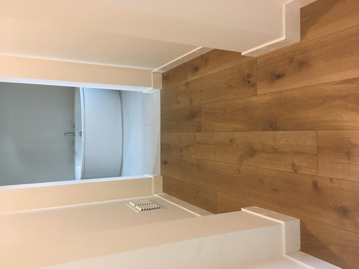 Wide plank white oak hallway leading to a freestanding tub