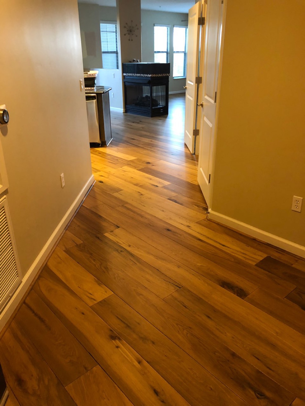 Hickory hallway leading into a kitchen with a fireplace