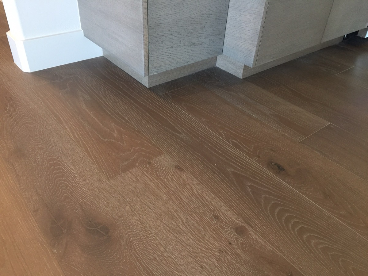 Close-up of wire-brushed wide plank oak beside grey cabinetry