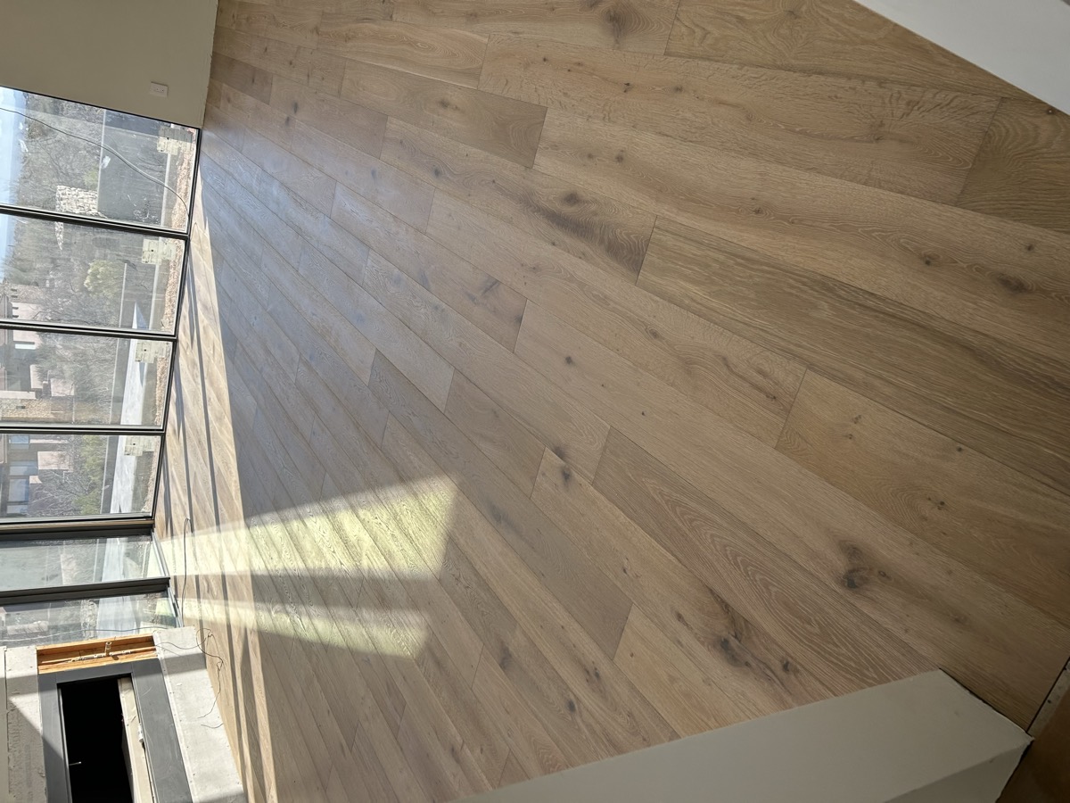 Sunlit room with glass walls and freshly installed wide plank oak
